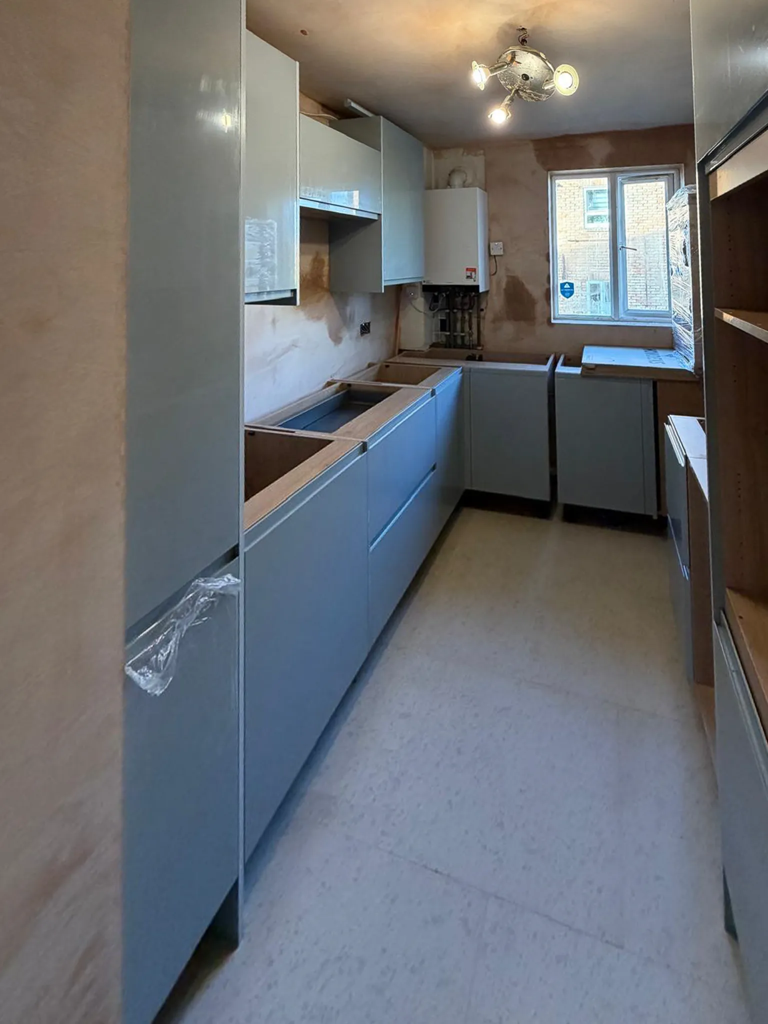 Grey kitchen carcasses installed in narrow galley layout during kitchen renovation in Surrey