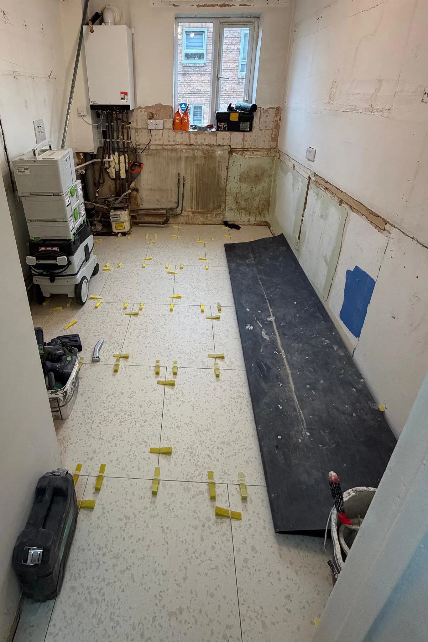 Kitchen floor tiling and plumbing preparation during galley kitchen renovation in Sutton Surrey