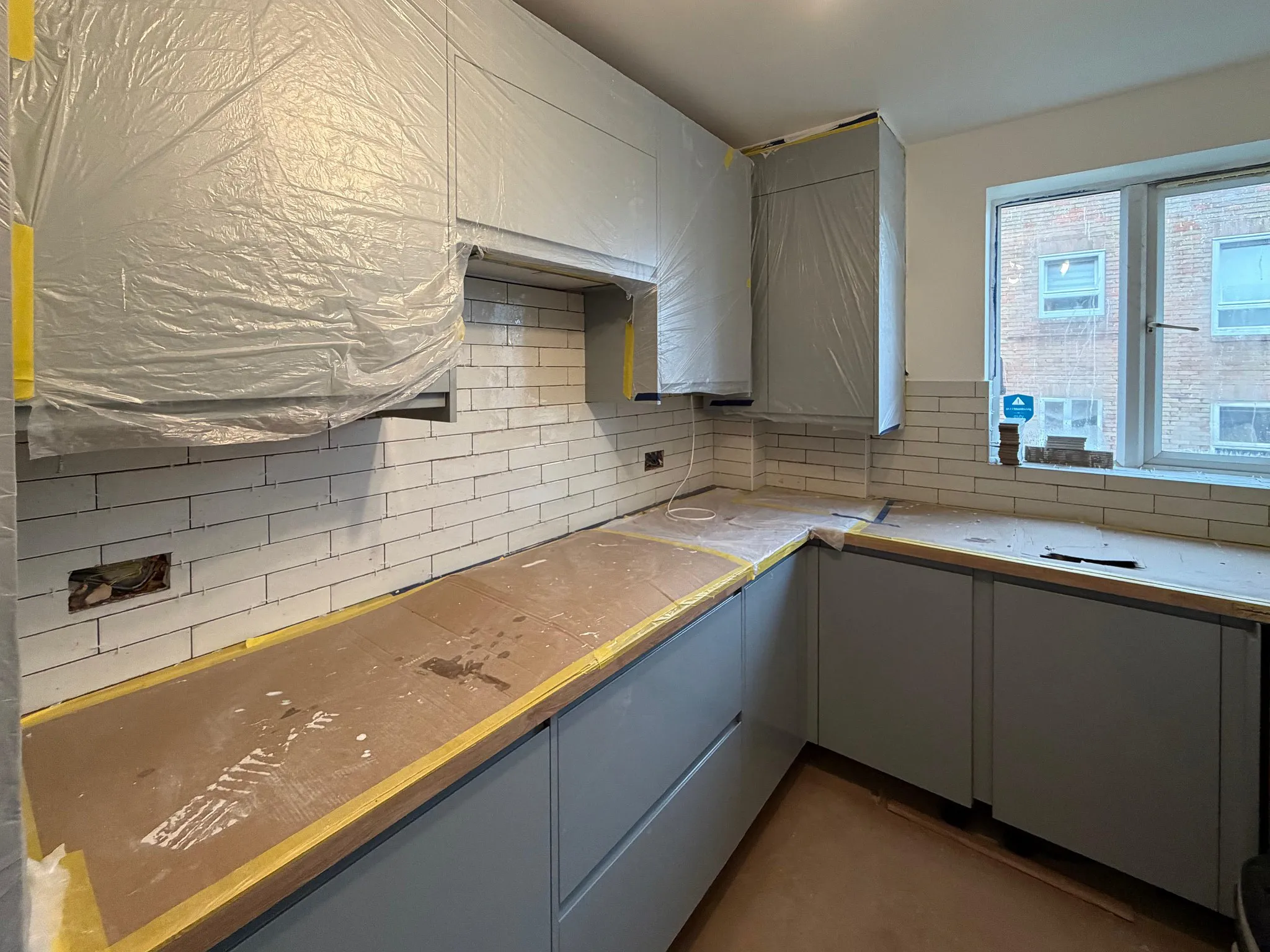 White subway tiles being laid as kitchen backsplash during galley kitchen renovation in Surrey