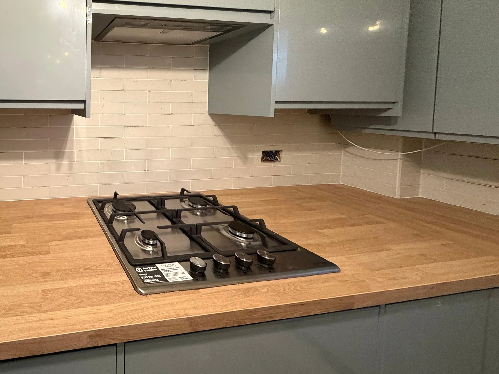 Modern narrow kitchen with grey handleless cabinets and integrated gas hob in Sutton Surrey