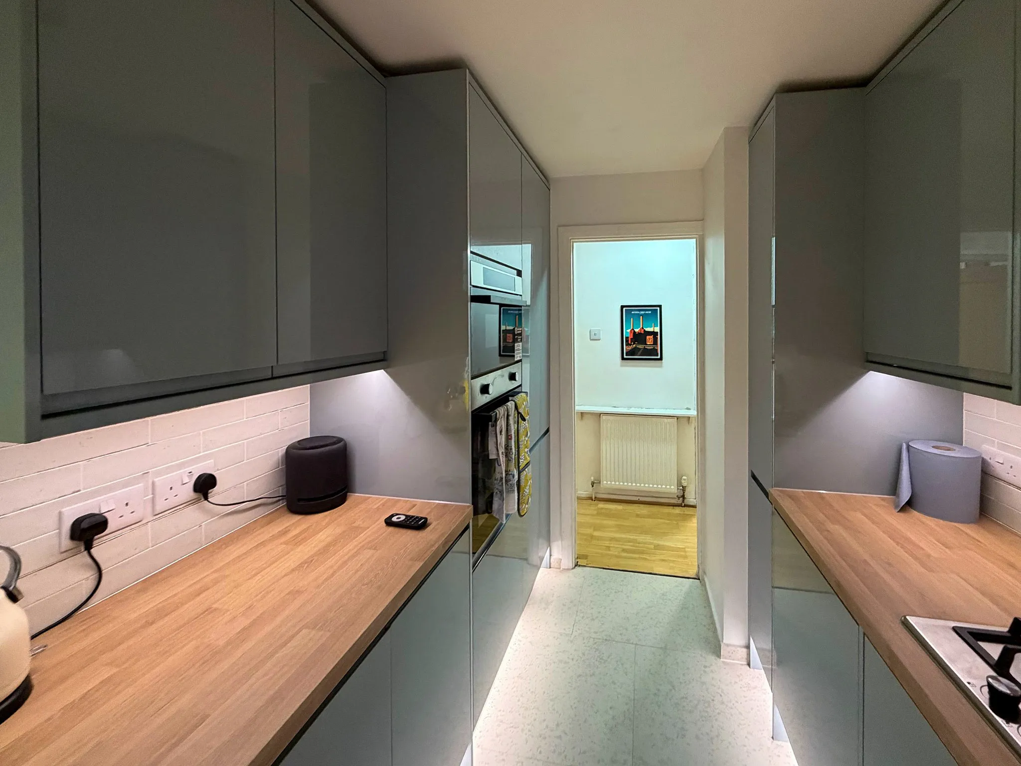 Completed narrow fitted kitchen with subway tile splashback and oak-effect worktop in Surrey