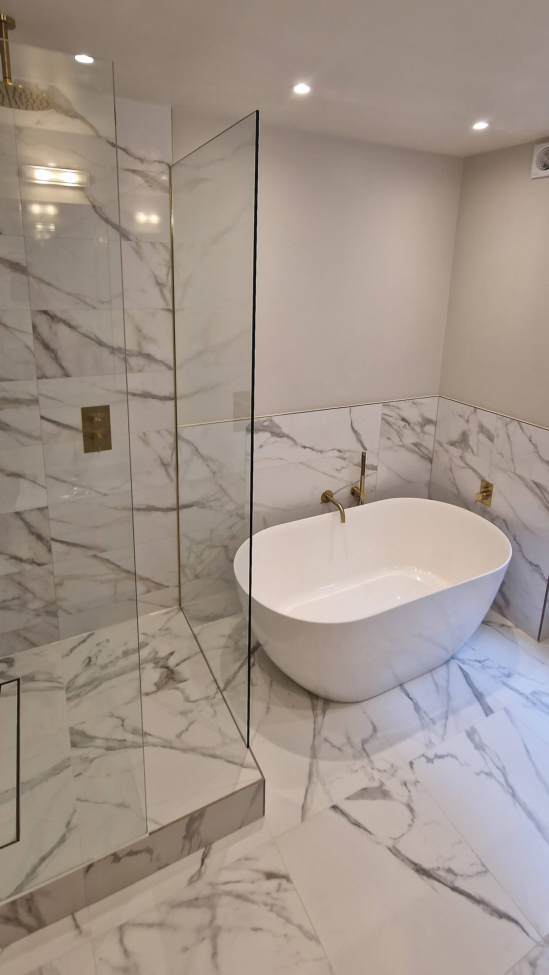 Freestanding oval bath with brass filler tap, Chelsea SW10 Freestanding oval bath with a brass filler tap against marble tiling, Chelsea SW10