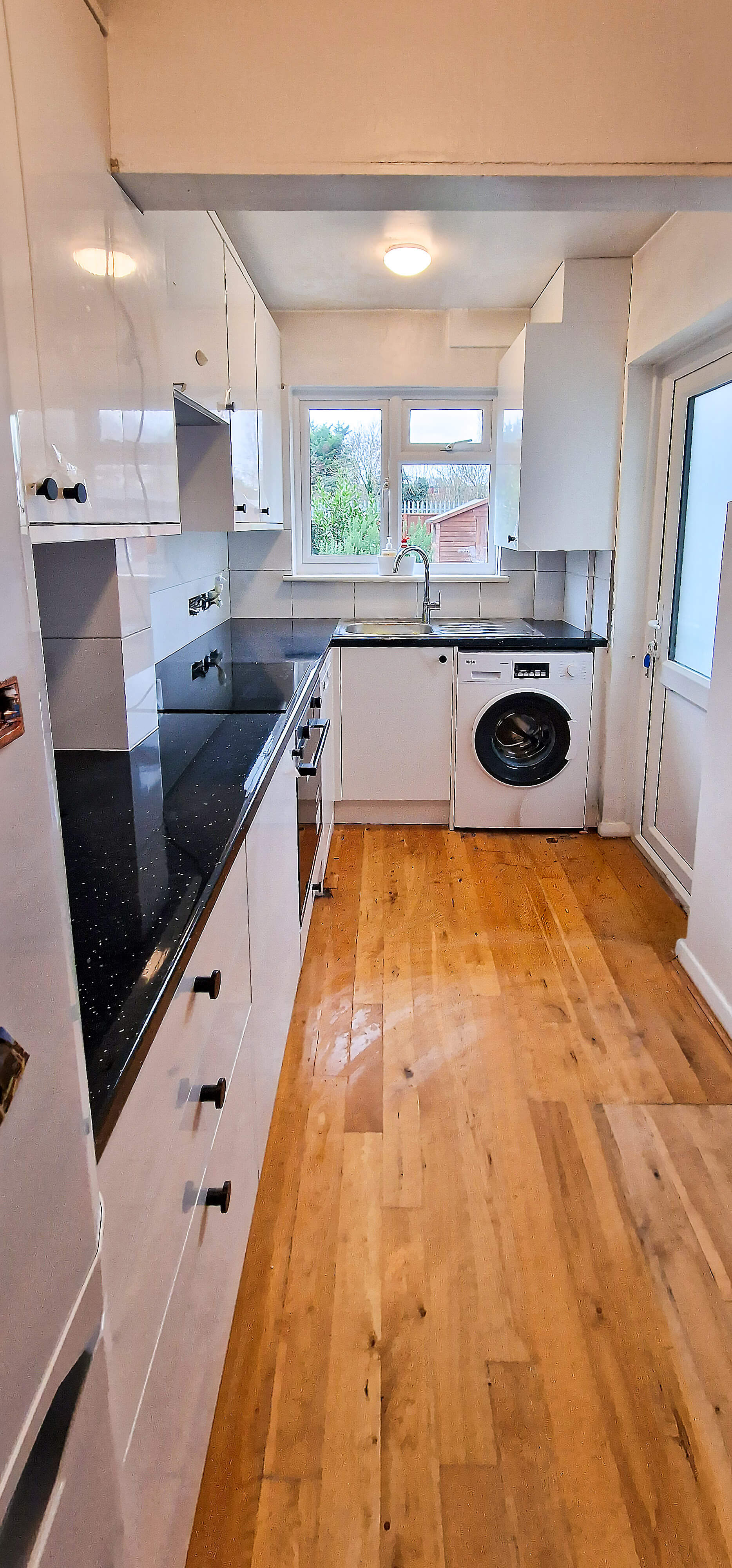 Kitchen in Wallington with new wood flooring and white gloss units, before final electrical connections