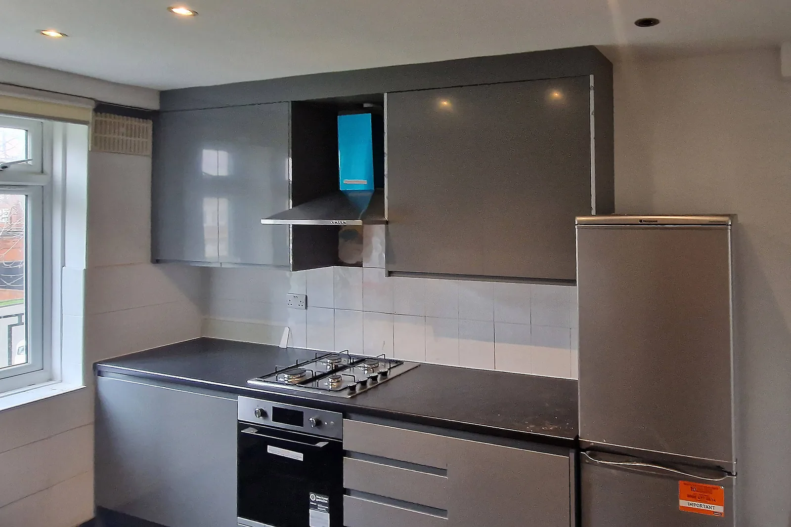 New fitted kitchen with grey gloss units and integrated gas hob in Carshalton SM5