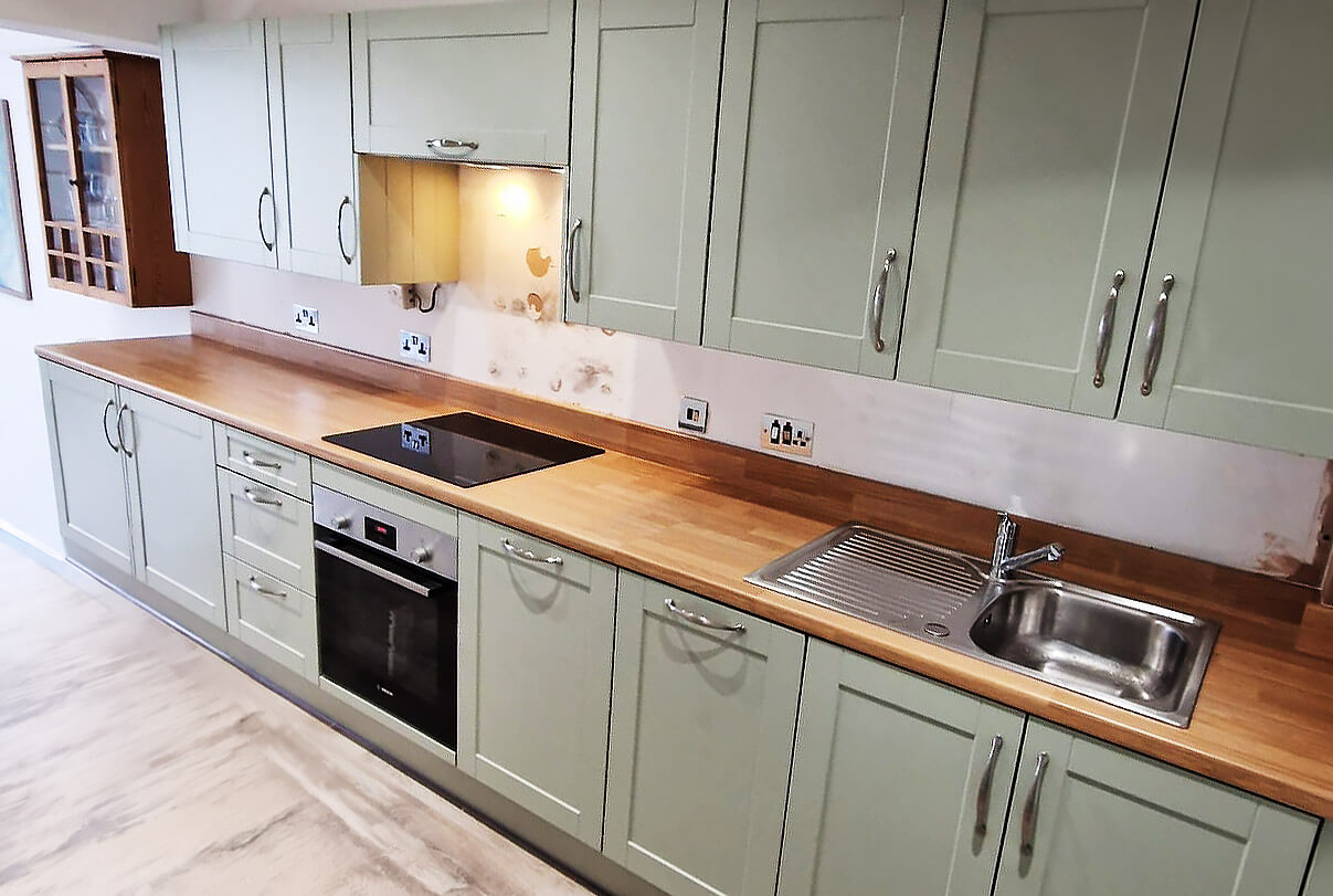 Finished sage green shaker kitchen with oak worktop after full renovation in Shepherds Bush