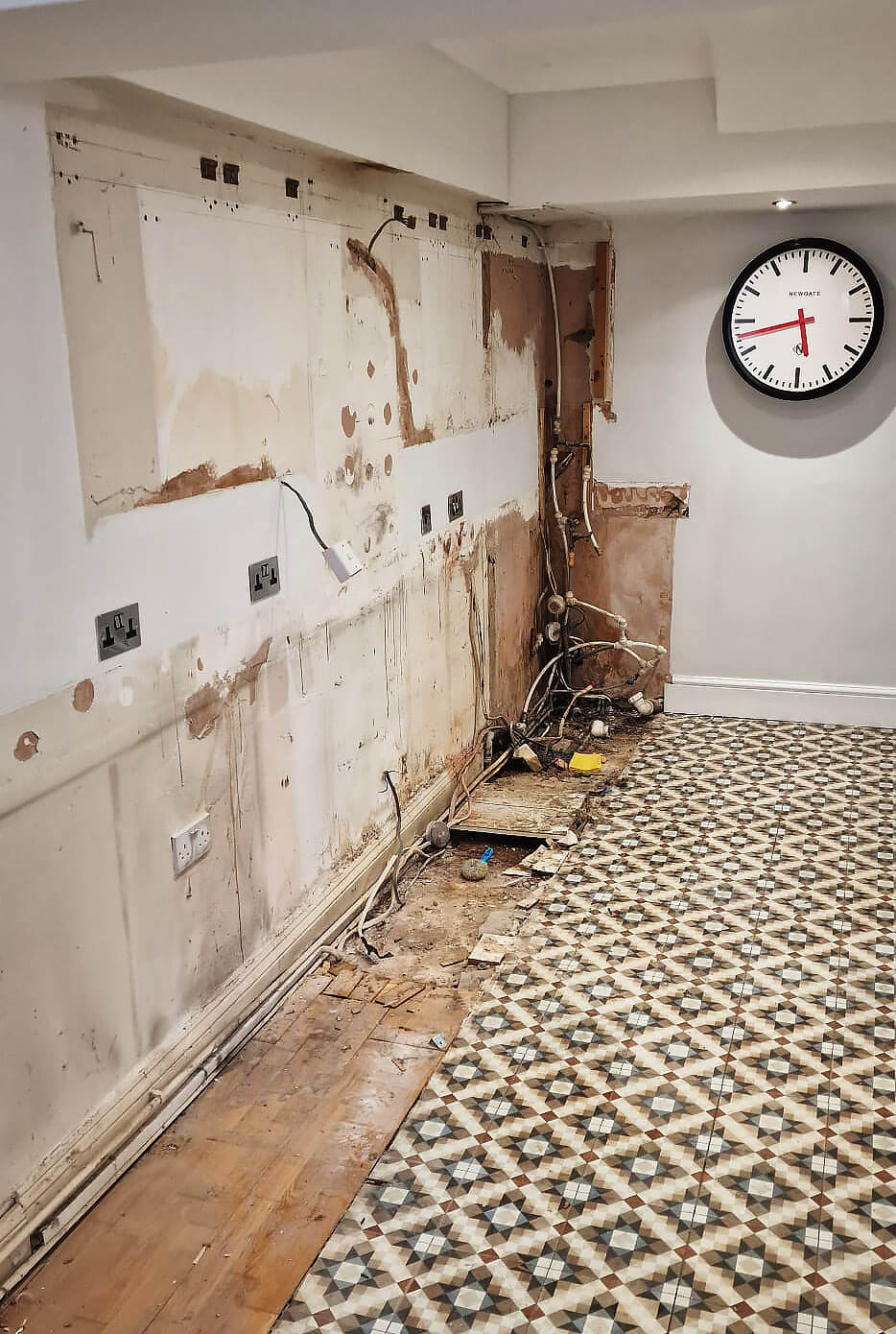 Kitchen walls stripped back with old wiring and pipework exposed during renovation in Shepherds Bush, London