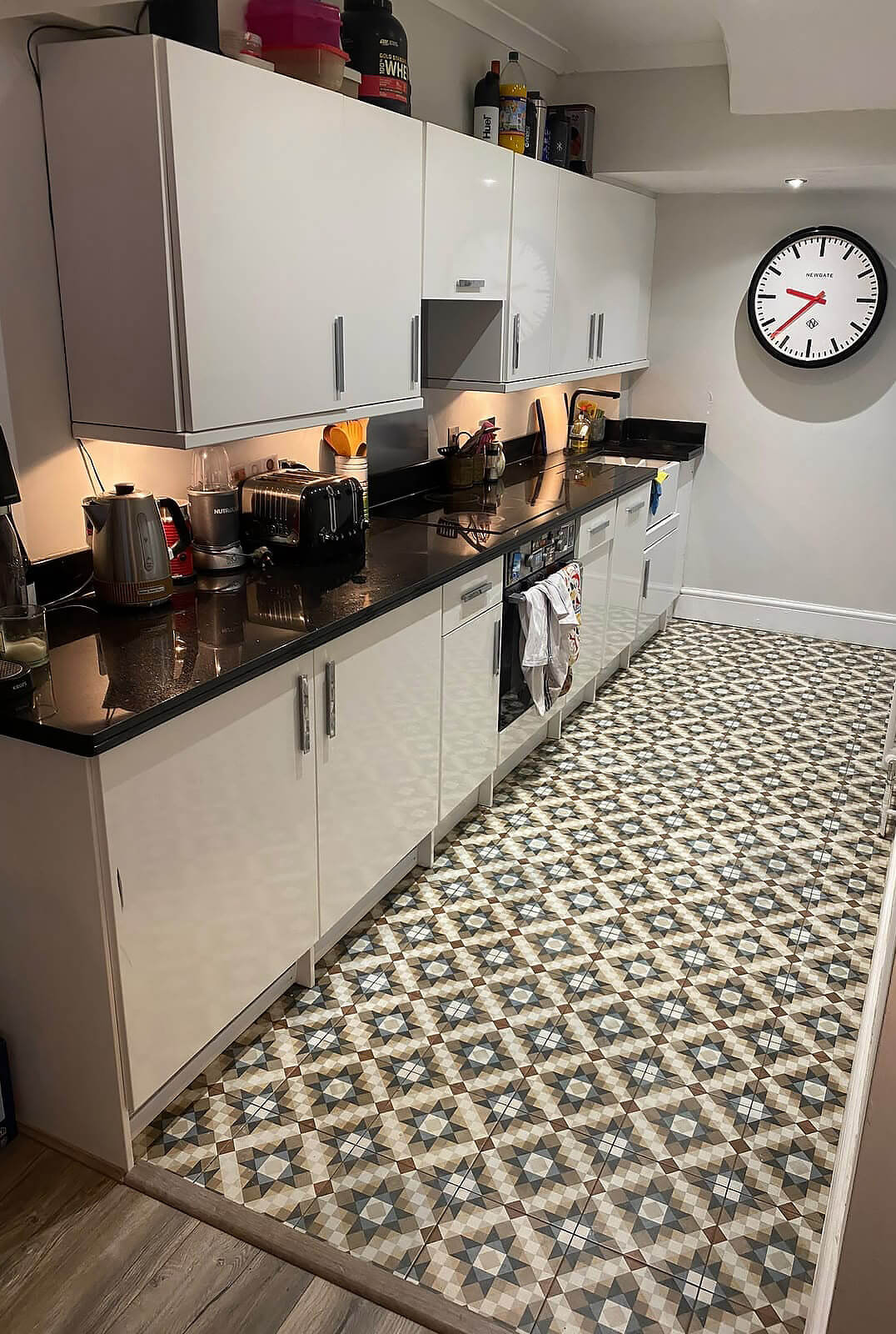 Old kitchen with black worktop and patterned Victorian floor tiles before renovation in Shepherds Bush