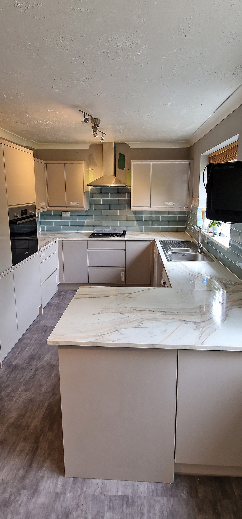 Kitchen peninsula with waterfall-edge marble-effect worktop and breakfast bar in Tooting, SW17