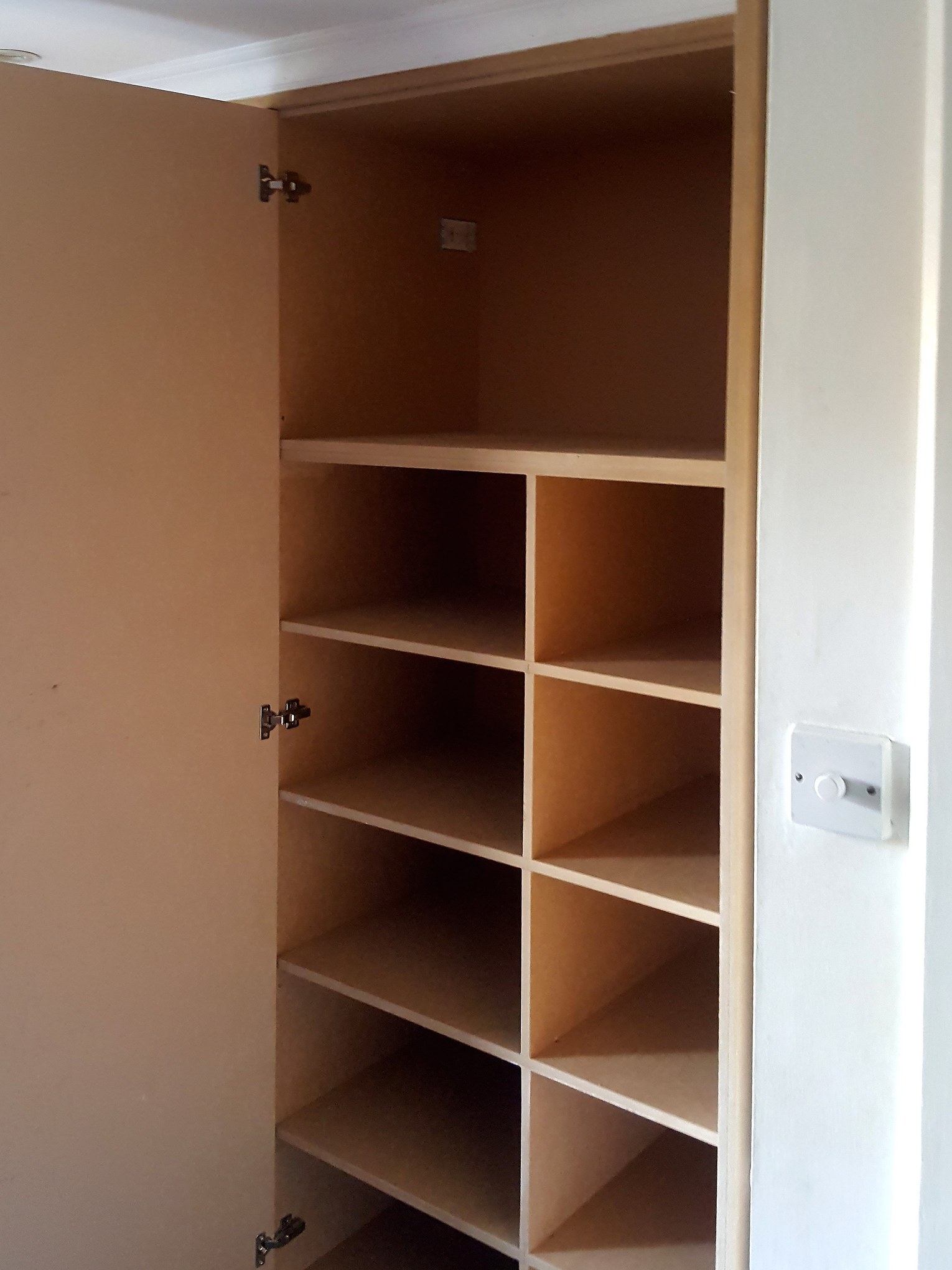 Built-in wardrobe: pigeonhole shelving Built-in wardrobe interior with pigeonhole shelving behind an open door