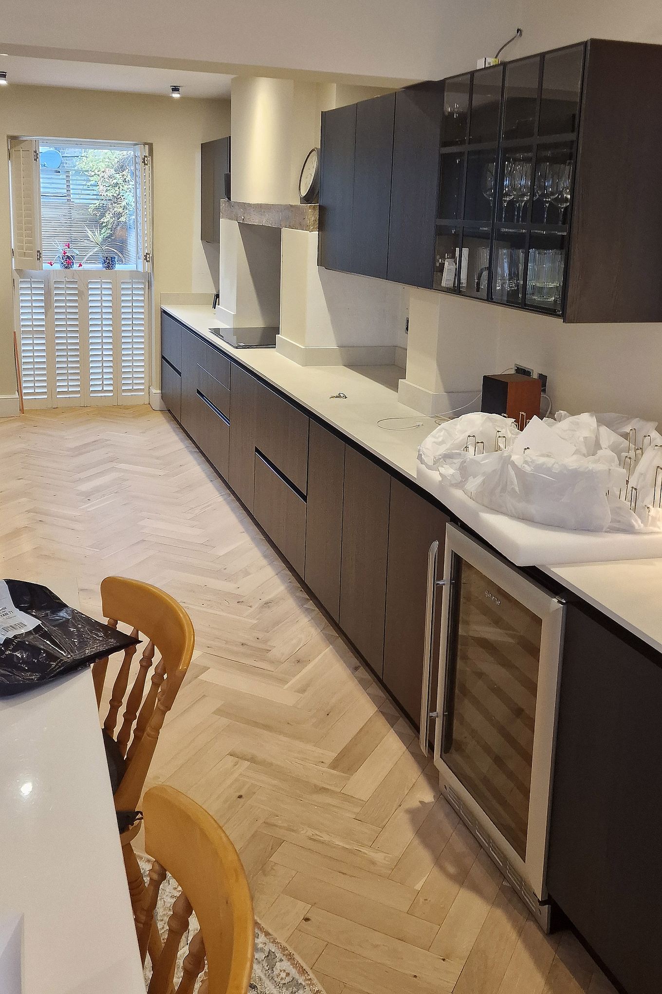 Fitted kitchen in Hampton Wick with dark handleless units, undercounter wine cooler and herringbone floor