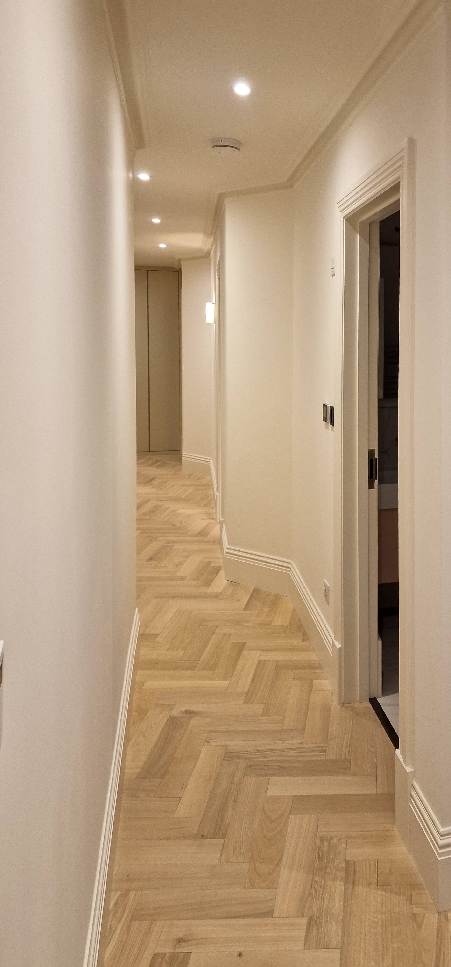 Completed hallway joinery with herringbone flooring, Chelsea SW10 Finished Chelsea hallway with herringbone parquet flooring and bespoke built-in joinery along the corridor, SW10