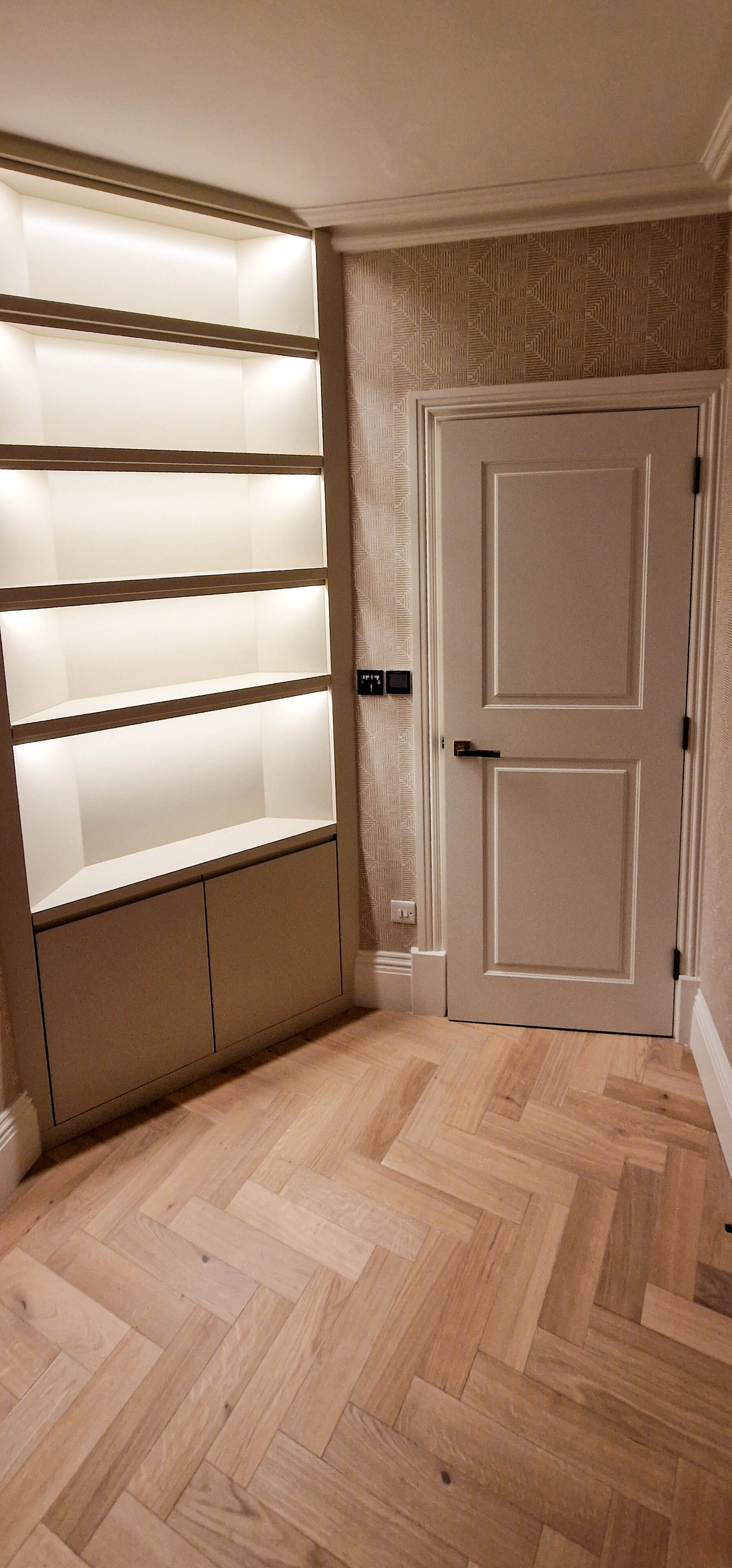 Bespoke shelving with integrated LED lighting, Chelsea SW10 Bespoke built-in shelving with integrated LED lighting fitted into an angled hallway corner in Chelsea, SW10