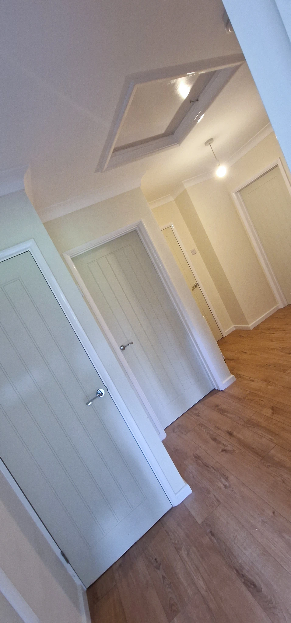 Howdens Dordogne moulded panel doors installed on a residential landing in Boxhill, Surrey Moulded panel internal doors fitted on a hallway landing in Boxhill, Surrey — Howdens Dordogne doors in white and sage green