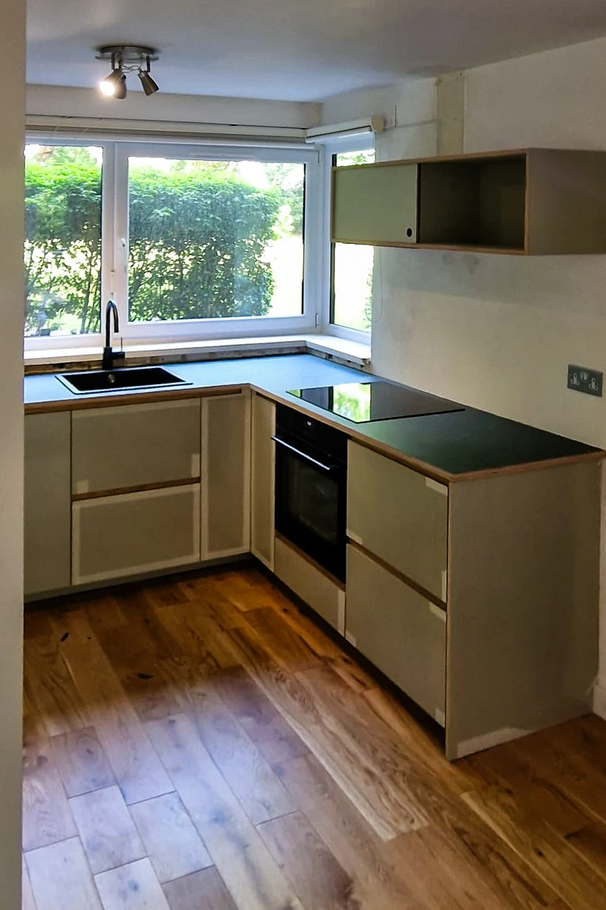 Completed kitchen installation in Wandsworth with sage green Plykea fronts on IKEA carcasses, dark laminate worktop and engineered oak floor
